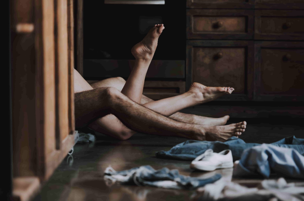 A man and woman obscured from view, having sex on the kitchen floor.